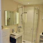 Badezimmer mit Dusche, Waschbecken und Spiegel