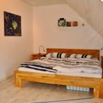 Schlafzimmer mit Dachschrägen, Holzbett und Nachttischen mit Lampen.