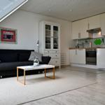 Wohnbereich mit Sofa, Couchtisch und Küche unter Dachschrägen.