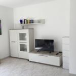 Wohnzimmer mit TV, Sideboard und Wandregal. Wandbild und Korb sind sichtbar.