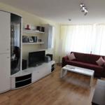 Wohnzimmer mit rotem Sofa, weißem Couchtisch und weißen Schränken.