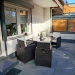 Terrasse mit Sitzgruppe und Holzverkleidung. Fliesenboden und Glasfront.