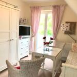 Schlafzimmer mit Bett, Tisch, Stühlen und TV. Fenster mit rosa Vorhängen.