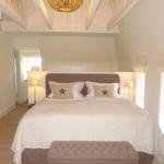 Schlafzimmer mit Bett, Nachttischlampen und Treppenhaus