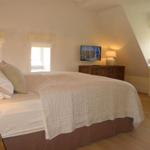 Schlafzimmer mit Bett, Fernseher und Fenstern.