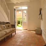 Eingangsbereich mit Sofa, Terrakottaboden und offenem Durchgang zur Außenterrasse.