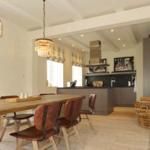 Essbereich mit Holztisch und Stühlen. Küche mit dunklen Schränken und Spüle.