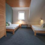 Zwei Einzelbetten, Kleiderschrank, Fenster und Wandlampen in einem Schlafzimmer.