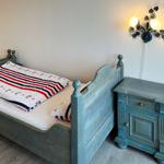 Schlafzimmer mit Bett, Nachttisch und Wandlampe.