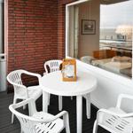 Terrasse mit weißem Tisch und Stühlen, roter Ziegelwand und Blick aufs Meer.
