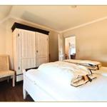 Schlafzimmer mit Bett, Kleiderschrank und Stuhl.