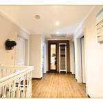 Hausflur mit Holzboden, weißen Türen und Wandbild. Treppenhaus links, Schrank rechts.