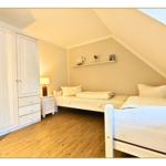 Zimmer mit zwei Betten, Kleiderschrank und Holzboden unter Dachschrägen.