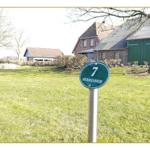 Grüner Hofzaun mit Schild 7 HERRENHOF. Im Hintergrund steht ein traditionelles Bauernhaus.