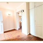 Hausflur mit weißen Schränken und Terrakottbodenfliesen. Durchgang zur Küche.