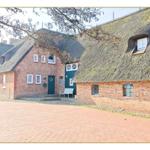 Roter Backsteinbau mit Strohdach und grüner Tür