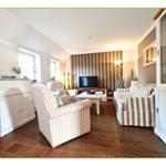 Wohnzimmer mit Sitzgruppe, Fernseher und Holzboden.