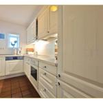 Küche mit weißen Schränken, Arbeitsplatte und Fenster.