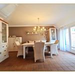 Esszimmer mit Esstisch, Stühlen und Schränken. Terrasse über Glastür.