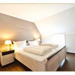 Schlafzimmer mit Bett, Nachttisch und Wanddekoration.