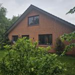 Rotes Backsteingebäude mit Fenstern und grünem Garten.