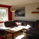 Wohnzimmer mit Ecksofa, Holztisch und Fenster mit Blick auf Grünfläche.