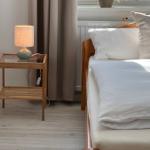 Schlafzimmer mit Bett, Nachttisch und Pflanze am Fenster.