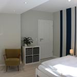 Schlafzimmer mit Bett, Stuhl und Regal an der Wand.