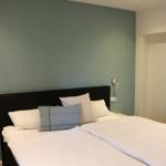 Schlafzimmer mit Bett, Wandbeleuchtung und Wandbild.