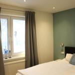 Schlafzimmer mit Bett, Fenster und grüner Wand
