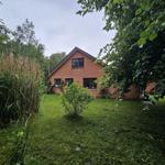 Rotes Backsteingebäude mit Garten und Bäumen.