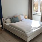 Schlafzimmer mit Doppelbett, zwei Nachttischen und Fenster mit Vorhängen.
