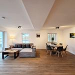 Wohn- und Essbereich mit Sofa, Esstisch und Holzboden.