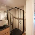 Dusche mit Glaswand, Waschbecken und Spiegel im Bad