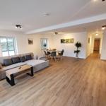 Wohn- und Essbereich mit Sofa, Tisch und Stühlen auf Holzboden.