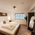 Schlafzimmer mit Bett, Fenster und Spiegel.