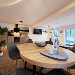 Essbereich mit Holztisch, Stühlen und Blick in die Küche.