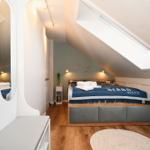 Schlafzimmer mit Dachschräge, Bett, Kleiderschrank und Dachfenster.