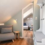 Eingangsbereich mit Kleiderschrank und Sitzbank. Durchgang zu Wohnzimmer mit Sofa.