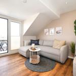 Wohnzimmer mit Sofa, Balkon und Wandregal. Holzboden und Dachschräge.