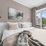 Schlafzimmer mit Bett, Wandbild und Fenster zum Balkon.