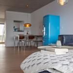 Ein Schlafzimmer mit Blick auf Wohnbereich und Küchenbereich mit blauem Kühlschrank.