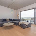 Wohnzimmer mit Sofa, Couchtisch und Blick auf Wasser