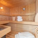 Holzsauna mit Banken, Handtuchstapel und Steinofen.