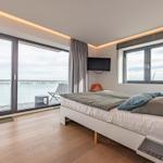 Schlafzimmer mit Blick auf Wasser, Bett, TV und Balkon.