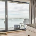 Zimmer mit Balkon und Blick auf Wasser und Häuser.
