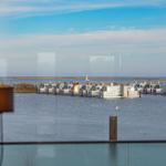 Blick auf Wasser und schwimmende Häuser mit Segelboot im Hintergrund.