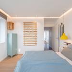Schlafzimmer mit Bett, Kleiderschrank und Fenster. Wandregal mit Haken.