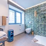 Bad mit Dusche, Toilette und Waschtisch. Wandfliesen mit tropischem Motiv.