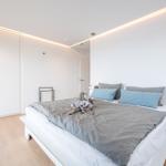 Schlafzimmer mit weißem Bett, grauer Bettwäsche und integriertem Schrank.